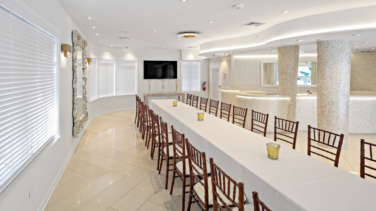 The image shows an elegantly decorated conference room with a long table, chairs, and candles, featuring modern lighting and a clean design.