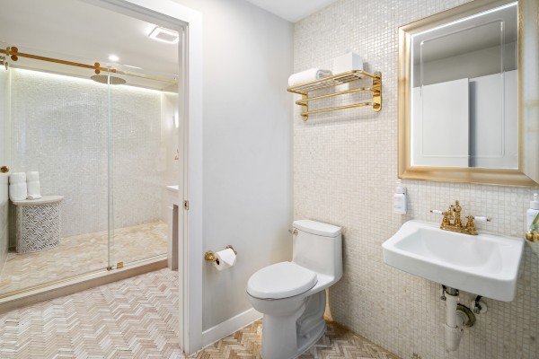 This image shows a clean, modern bathroom with a sink, toilet, mirror, and glass-enclosed shower.