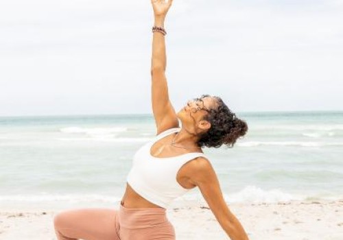 A woman practicing yoga on the beach, in a low lunge pose with one arm raised, enjoying a serene moment by the sea.